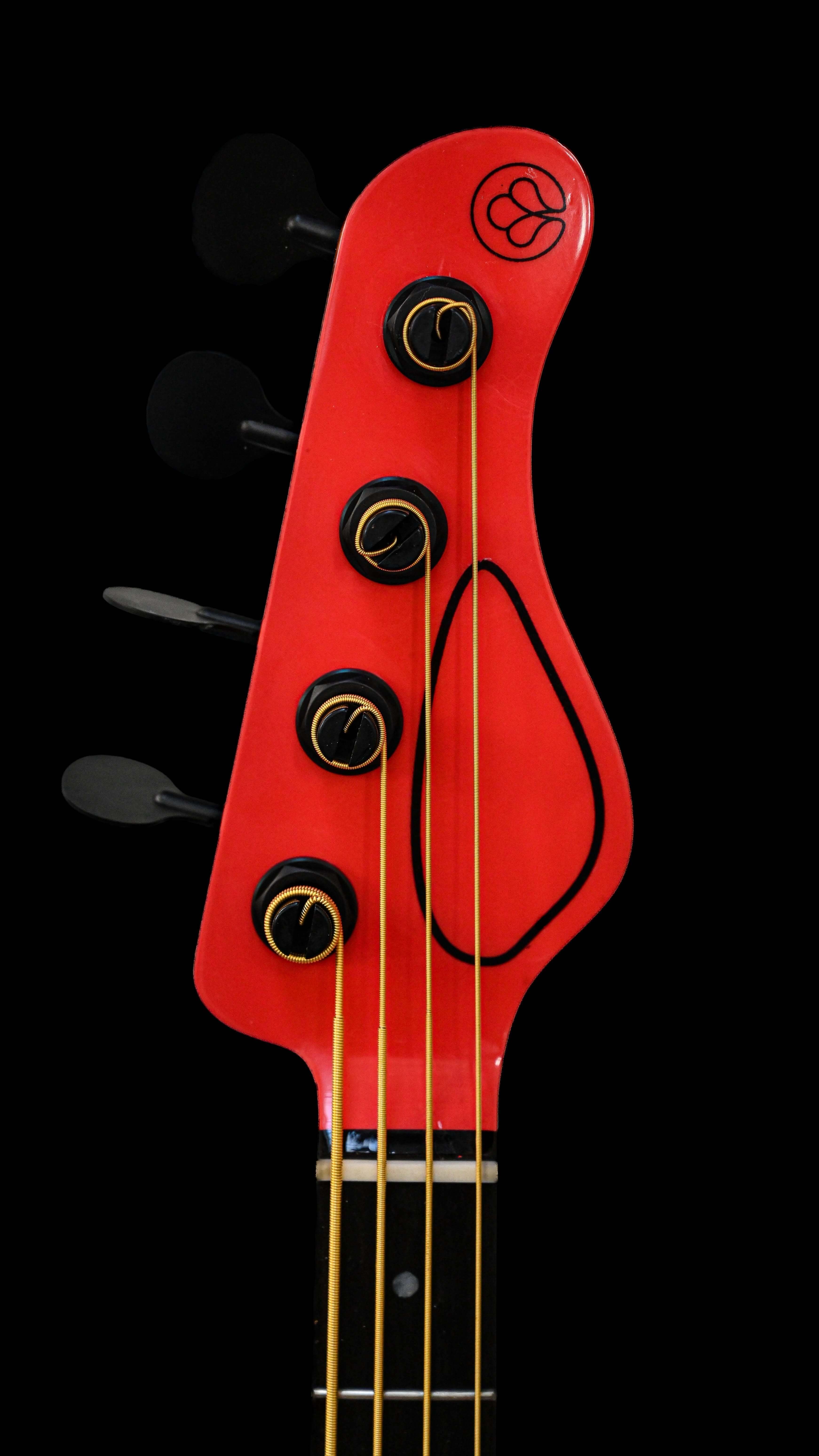 Strings Attached: Understanding Guitar and Bass Strings - Close-up of red bass guitar headstock.