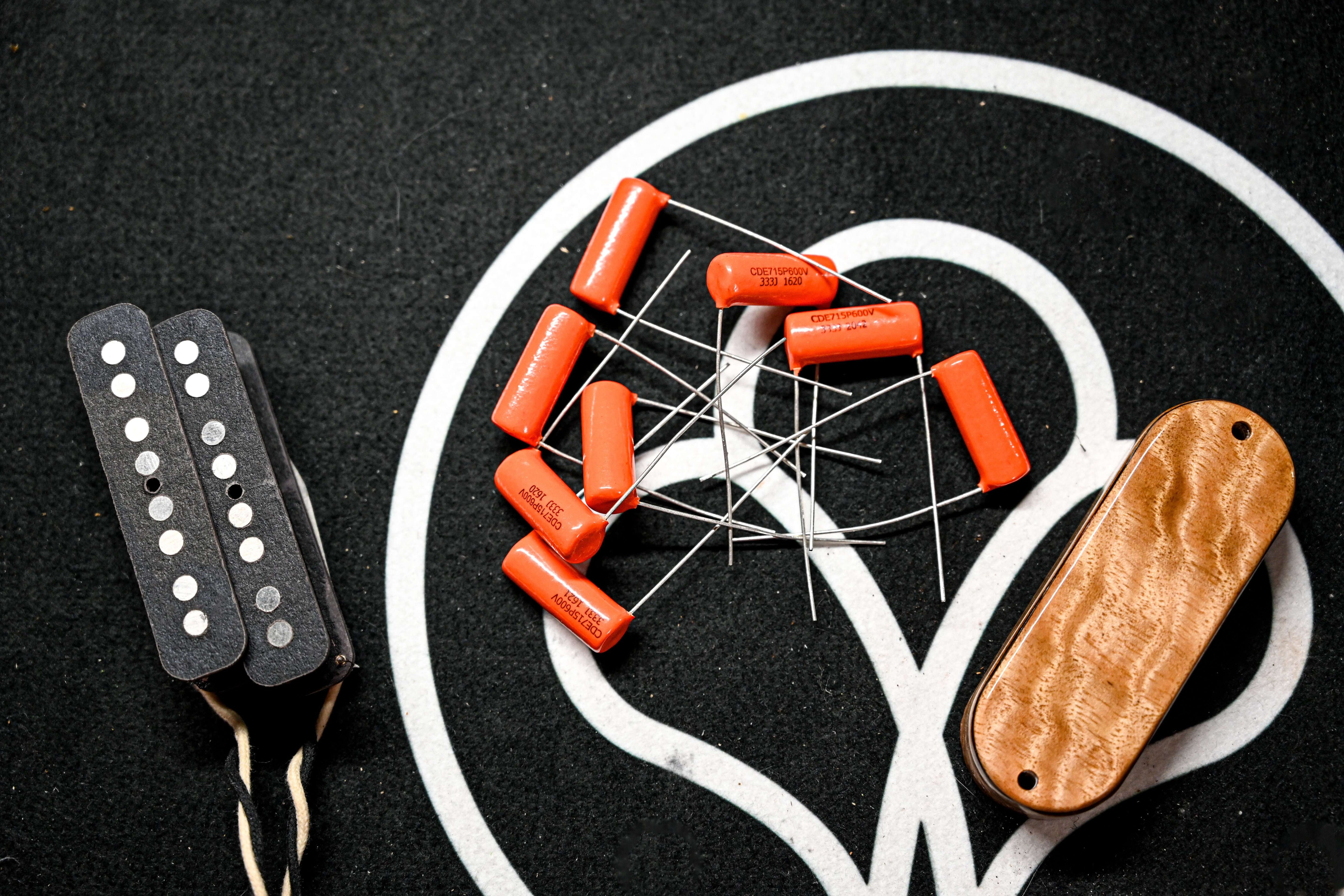 Belforti pickups, pickup shells and capacitors over a black background with the Belforti Logo