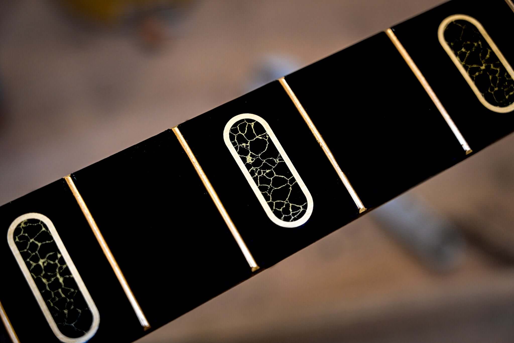 A close shot of the Belforti S1 Laudate Concordia bass fretboard, highlighting the incredible inlays made out of reconstituted stone