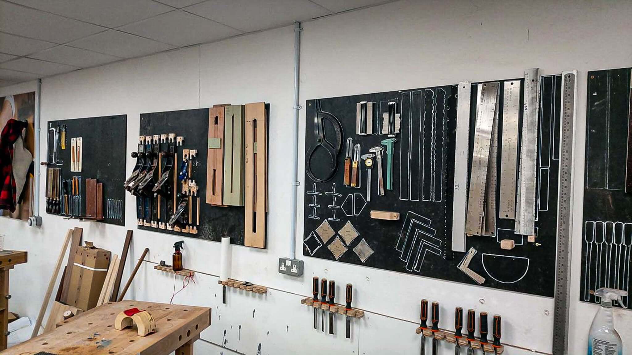 木工车间,工具整齐地排列在钉板和工作台上。