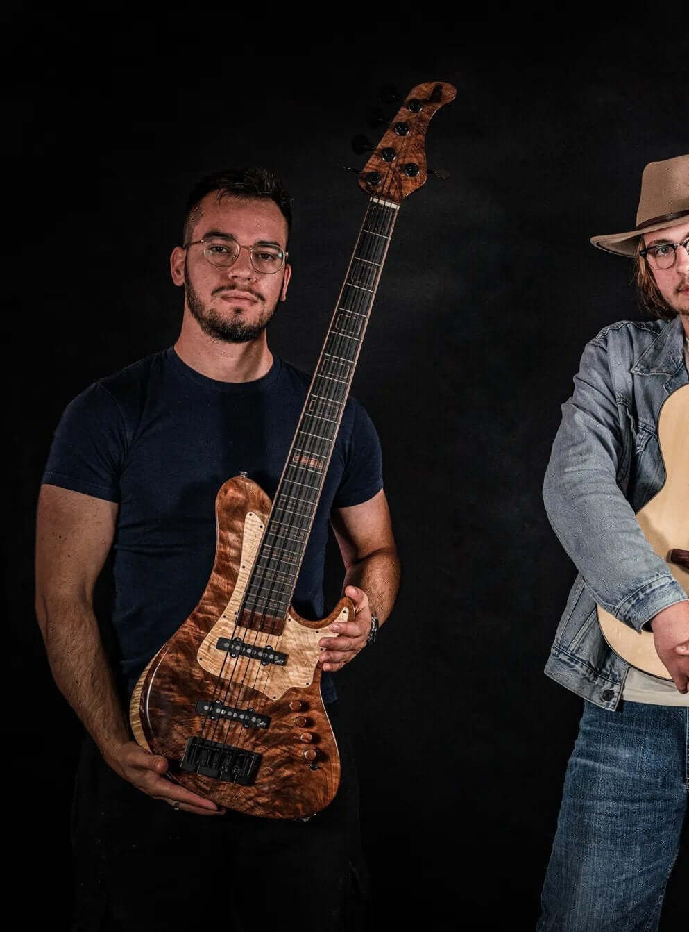 Two musicians posing with custom guitars, one holding a distinctive Belforti design, set against a dark background.