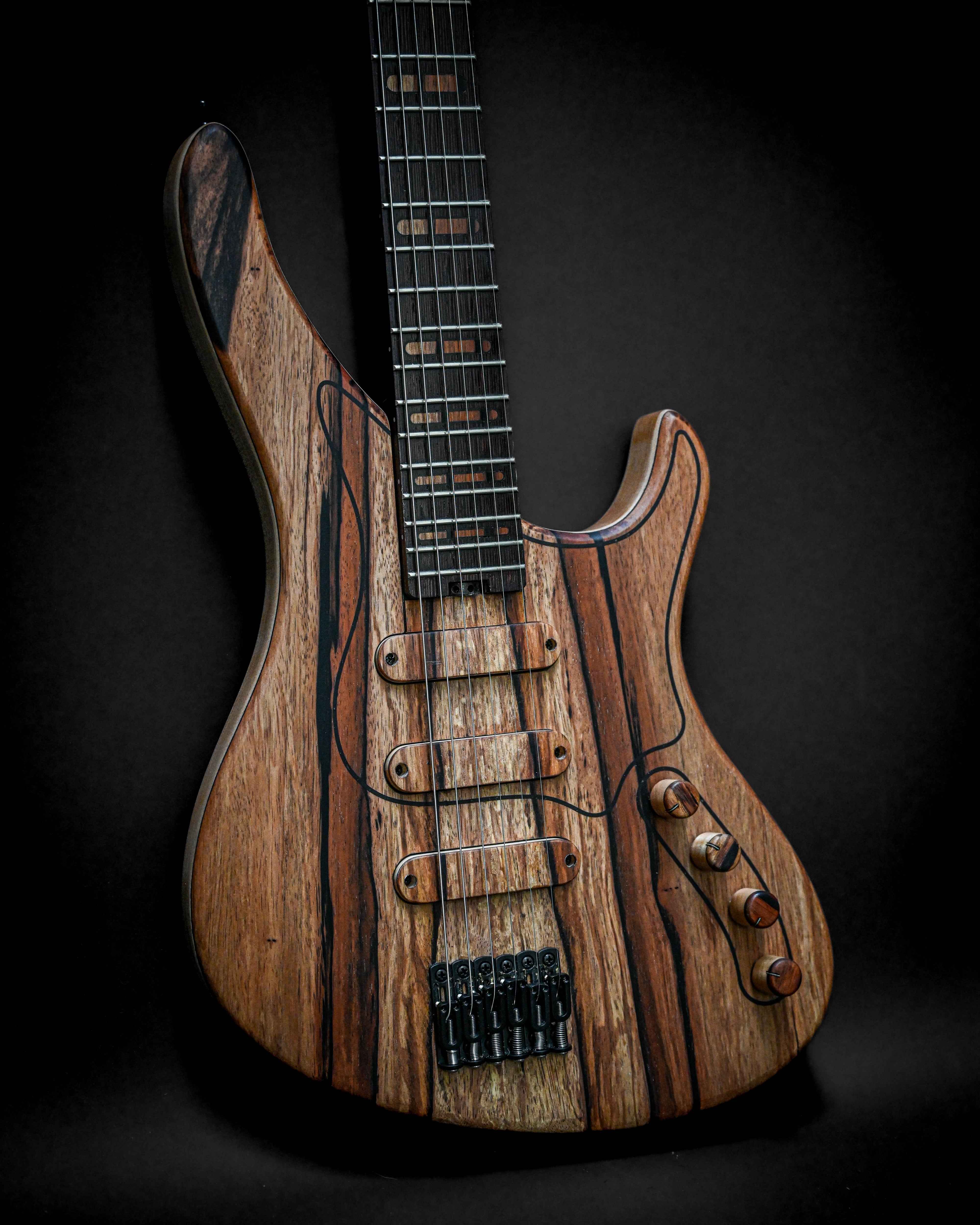 Close-up of a polished wooden electric guitar on a dark background with intricate grain patterns and six strings.