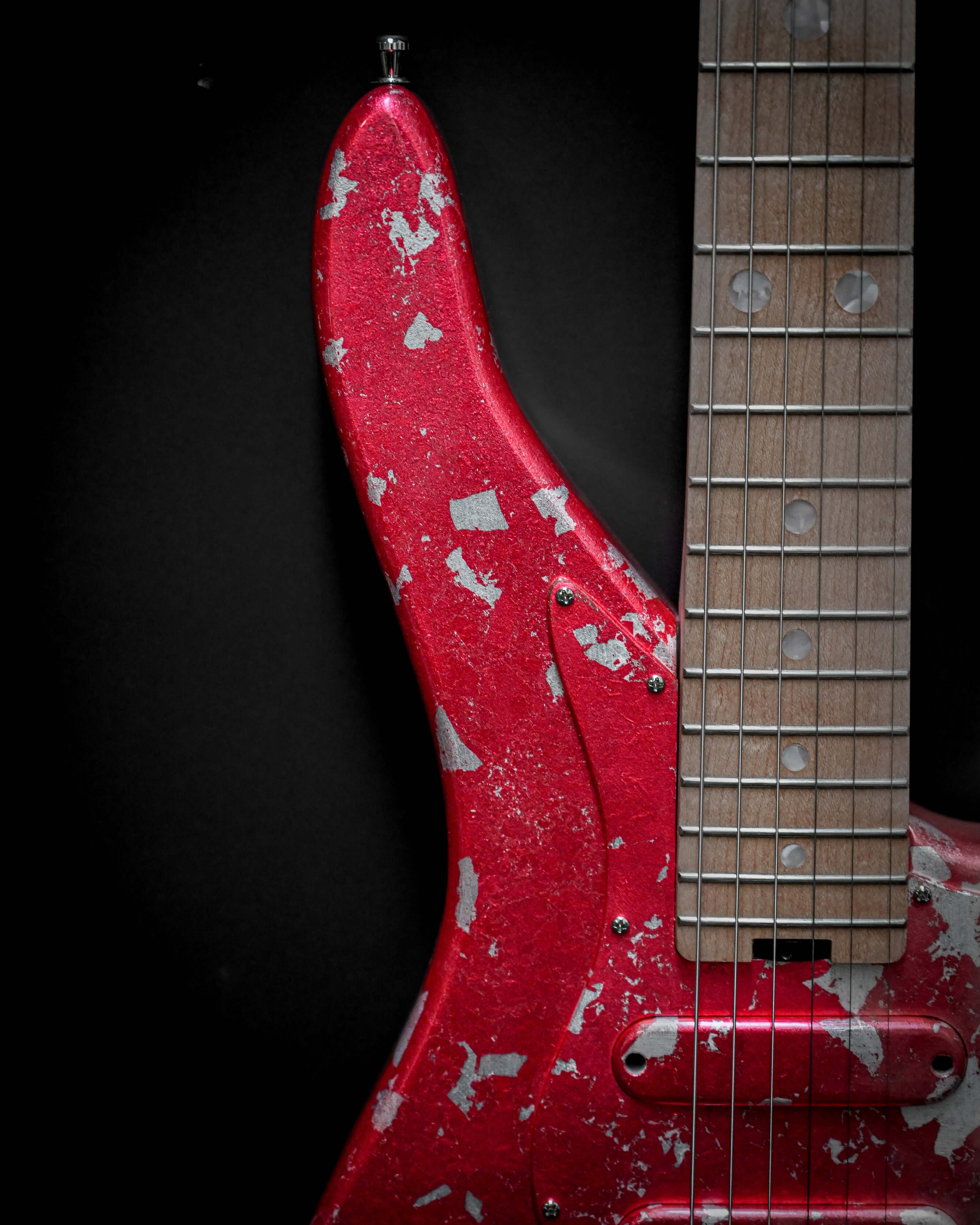 ベルフォルティのEシリーズに属する「Yatē 6 - Essential - Kurenai」カスタム・エレクトリック・ギターのクローズアップ。赤色のフィニッシュには使い込まれた風合いがあり、指板は木製です。