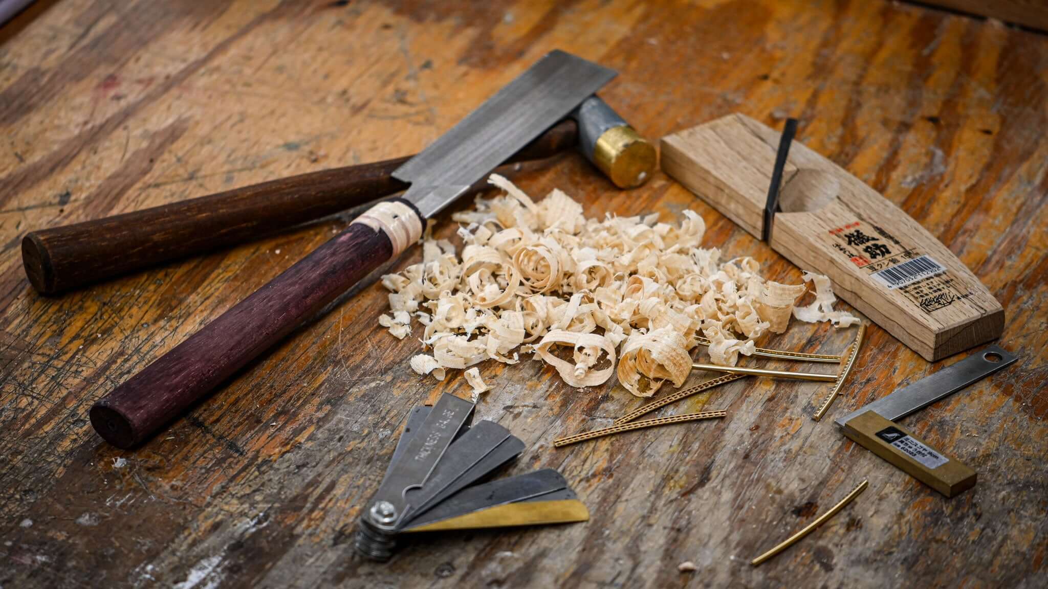 Belforti Woodworking tools, including chisel and saw, with shavings on a workbench, emphasizing craftsmanship