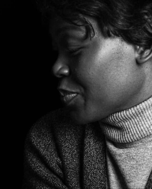 Black and white photo of a person in a turtleneck sweater, eyes closed, with a serene expression.