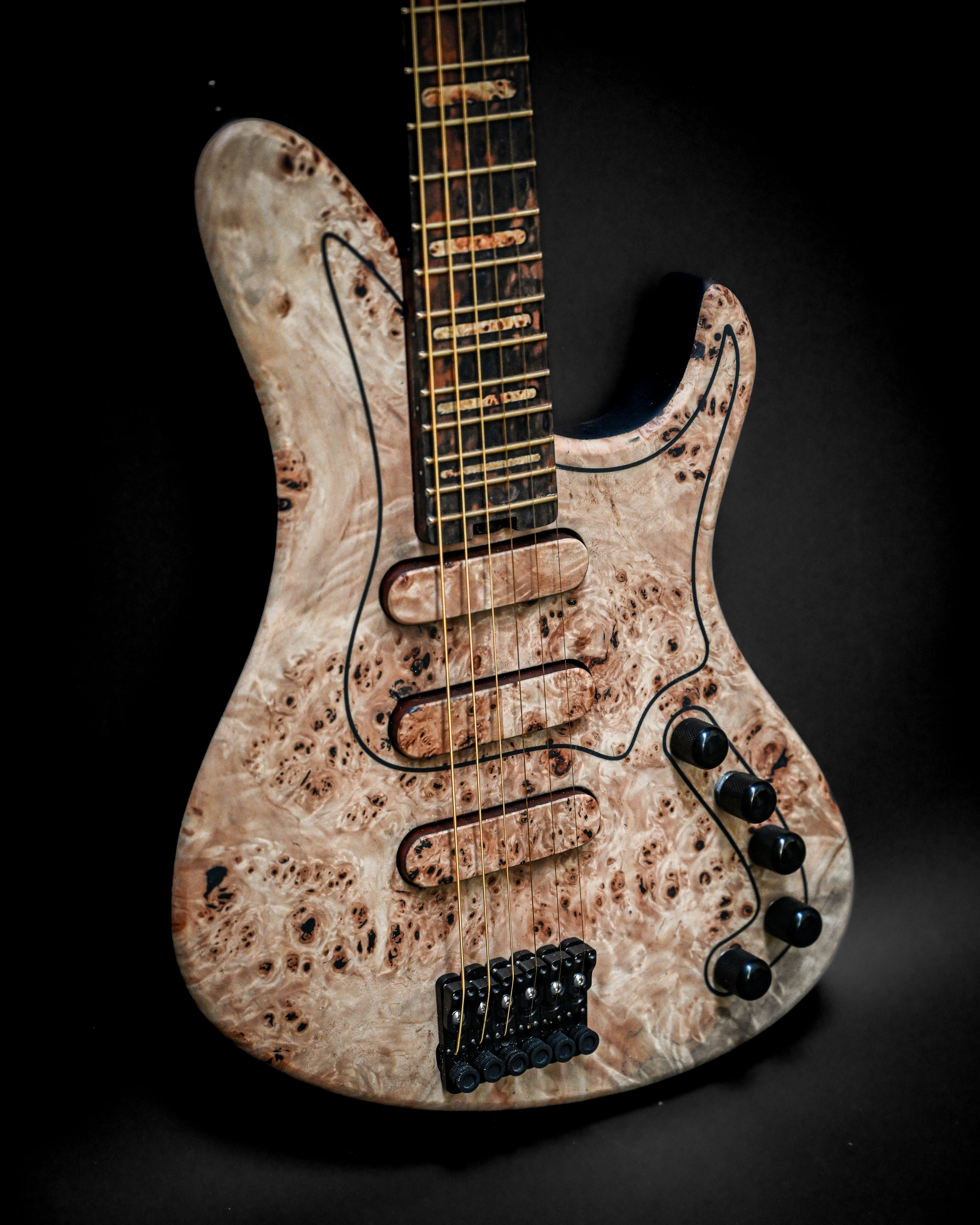 Close-up of an electric guitar with a unique burl wood finish and black hardware, set against a dark background.