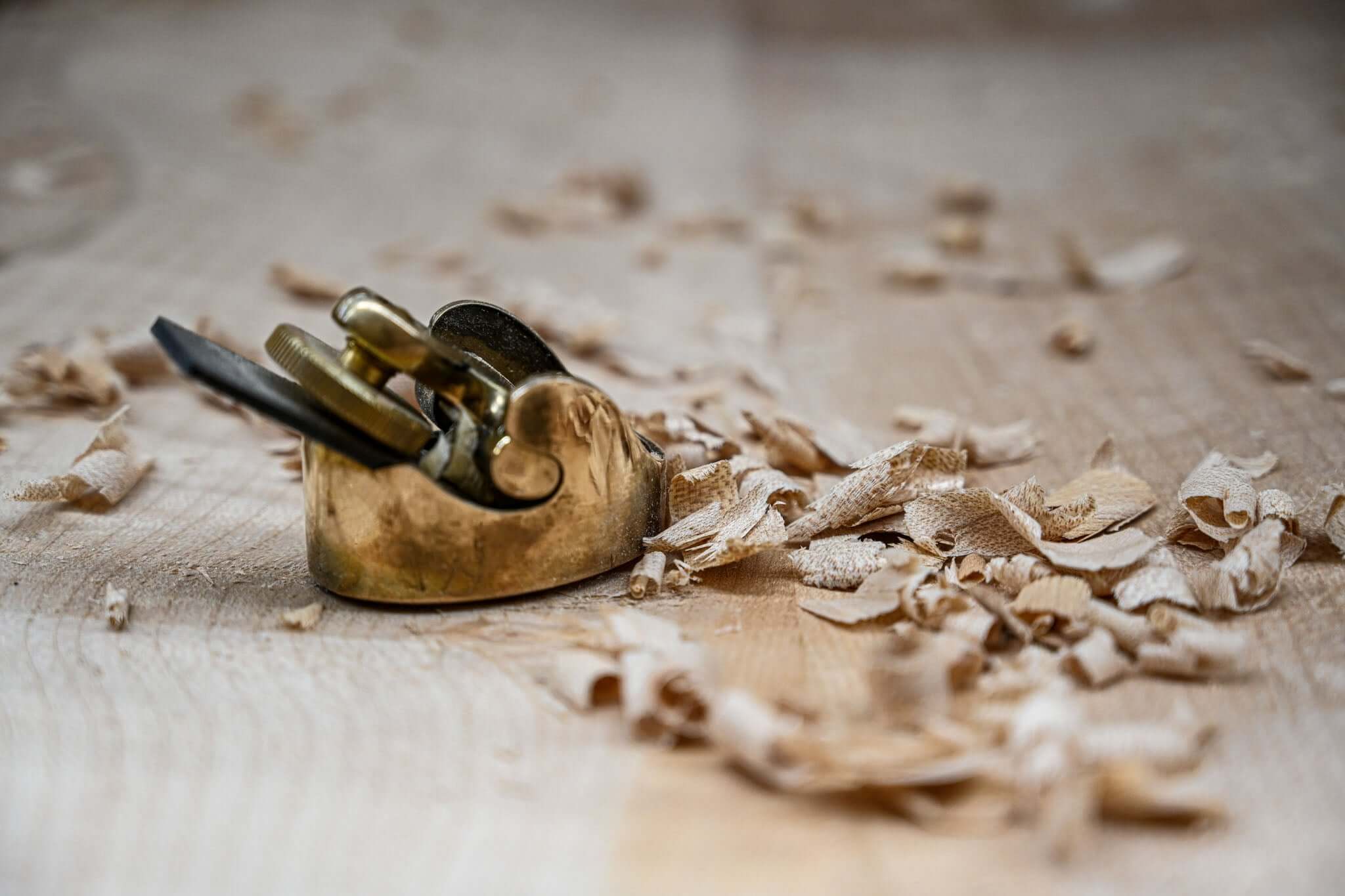 Cepillo de carpintería en un banco de trabajo rodeado de virutas de madera, destacando la artesanía de Belforti.