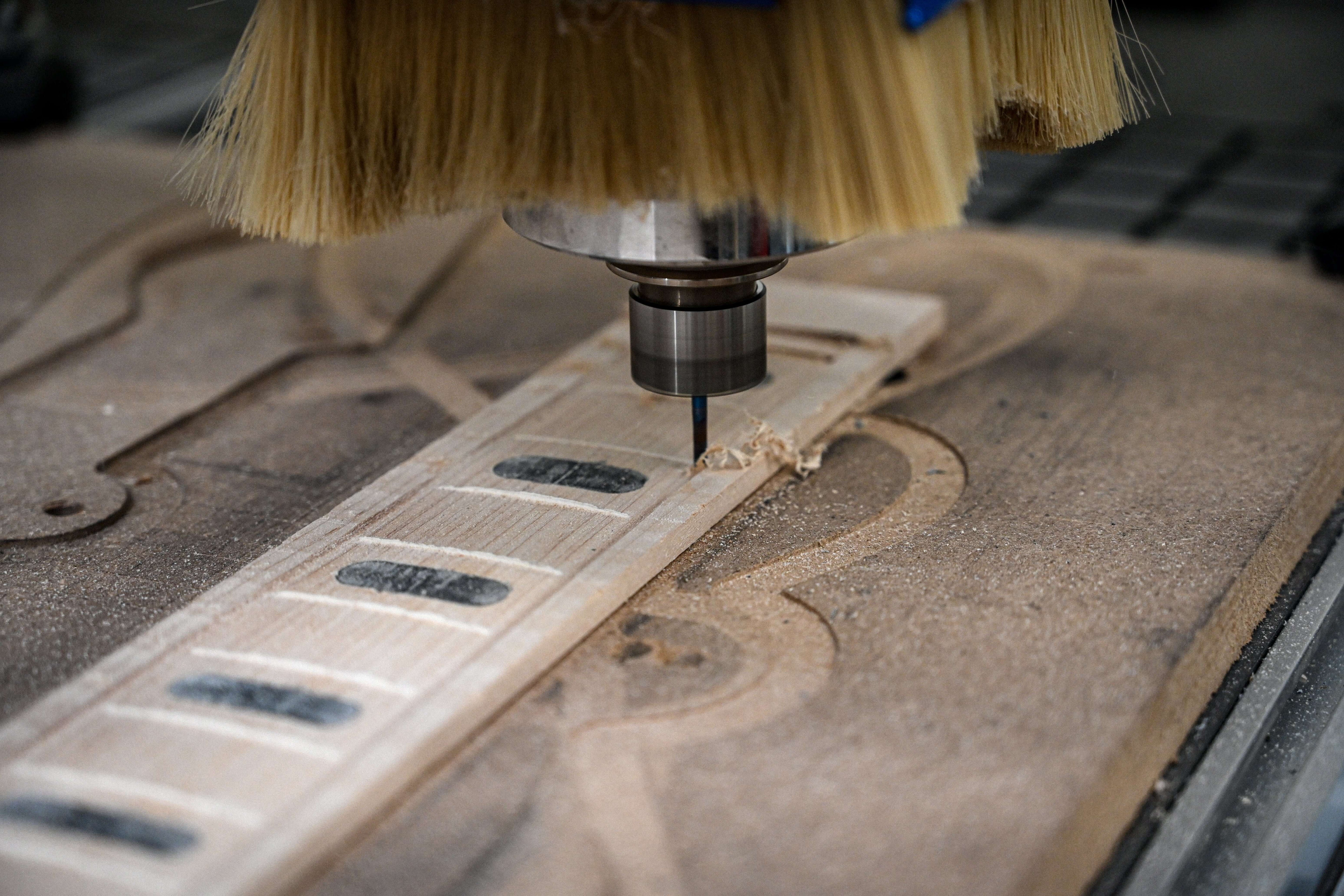 Una vista cercana de un diapasón de arce que está siendo mecanizado por una máquina CNC en la Manufactura de Guitarras Belforti en París