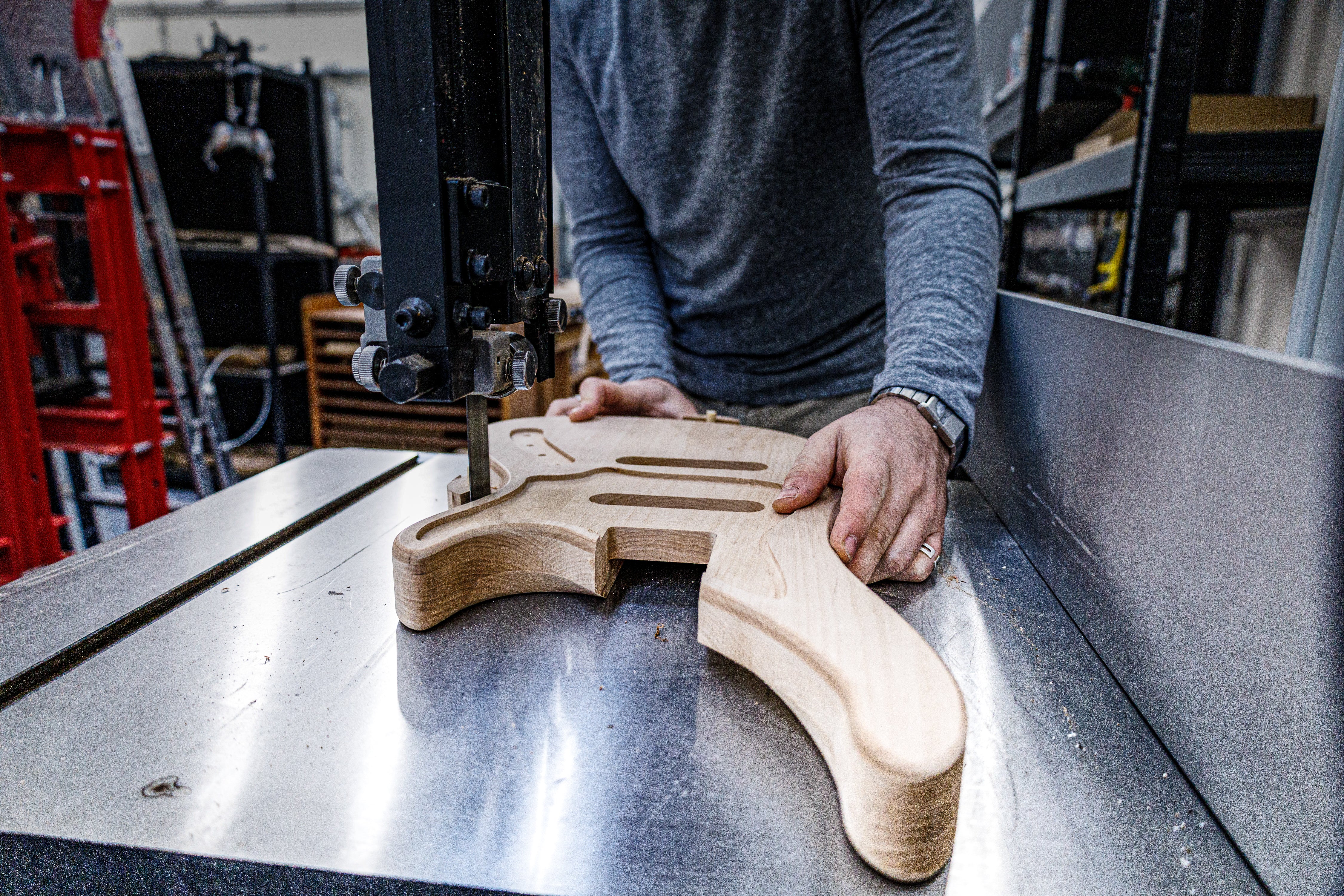 Artisan façonnant le corps d'une guitare dans un atelier pendant le cours de 6 semaines de construction de guitares et de basses personnalisées à Paris.