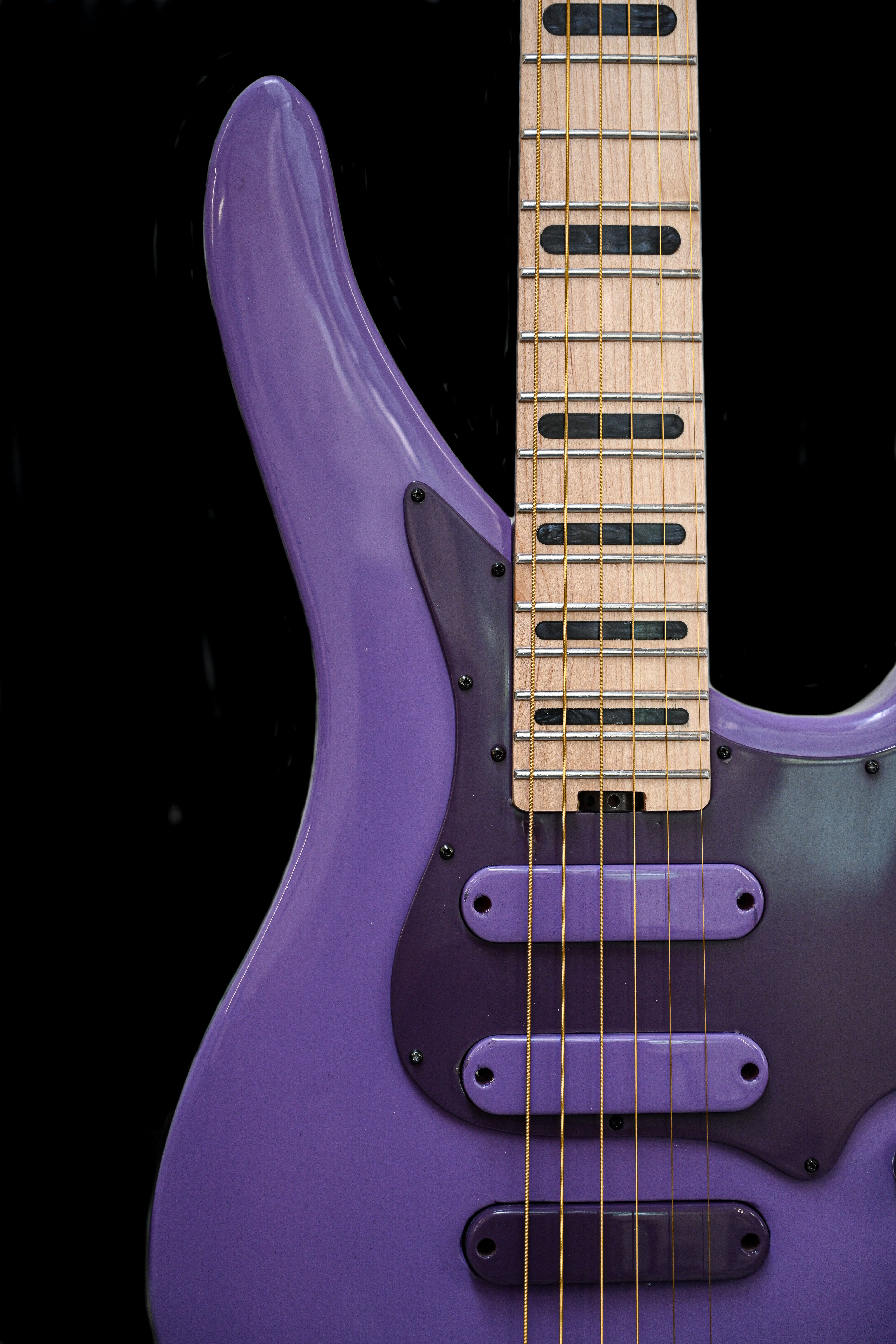 Vista em grande plano da guitarra E5 French Lilac, destacando o seu corpo roxo único e a escala detalhada.