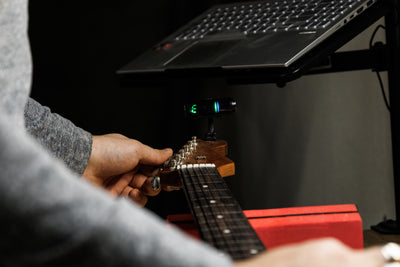 Hands adjusting guitar during Setup & Professional Instrument Care Course in Paris workshop.