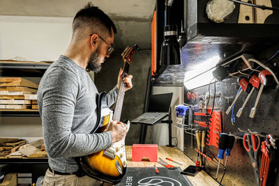 Participant adjusting guitar in Setup & Professional Instrument Care Course in Paris workshop environment.