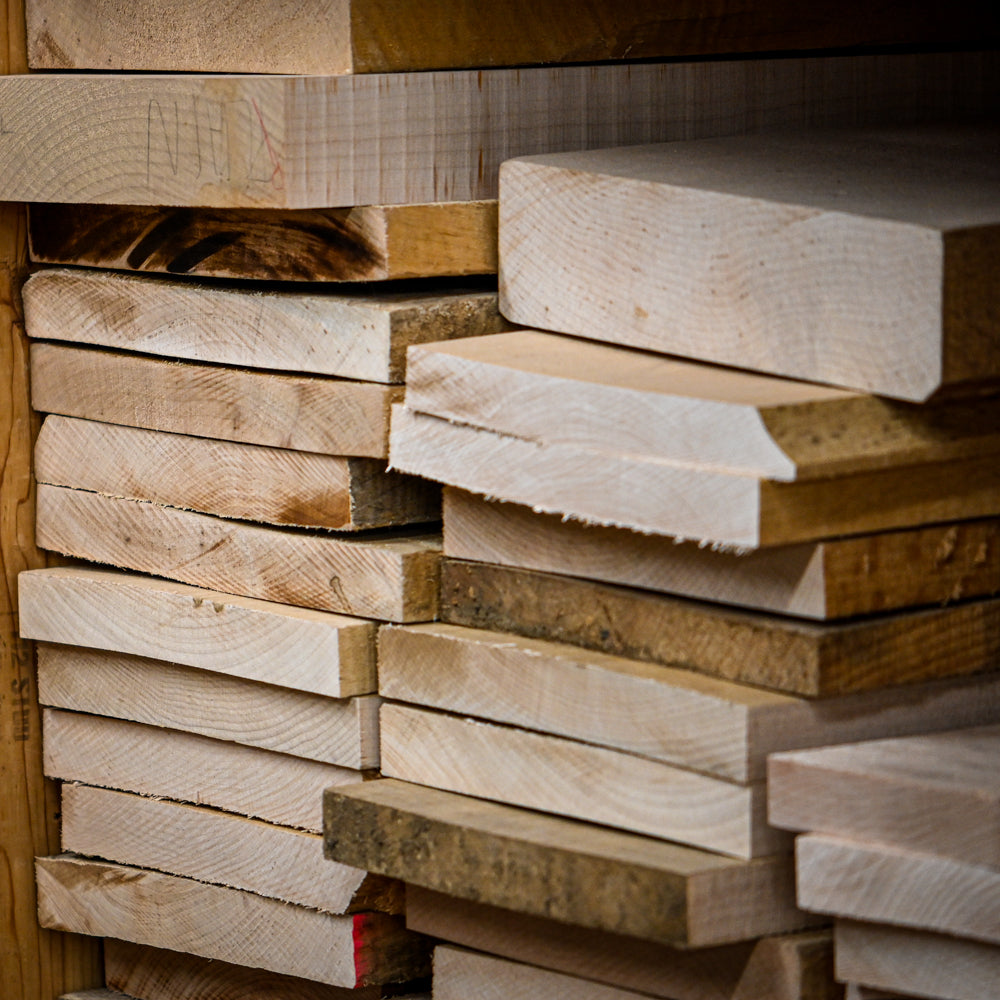 Stacks of various tonewoods, showcasing a selection of high-quality wood for musical instrument construction used at Belforti Instruments