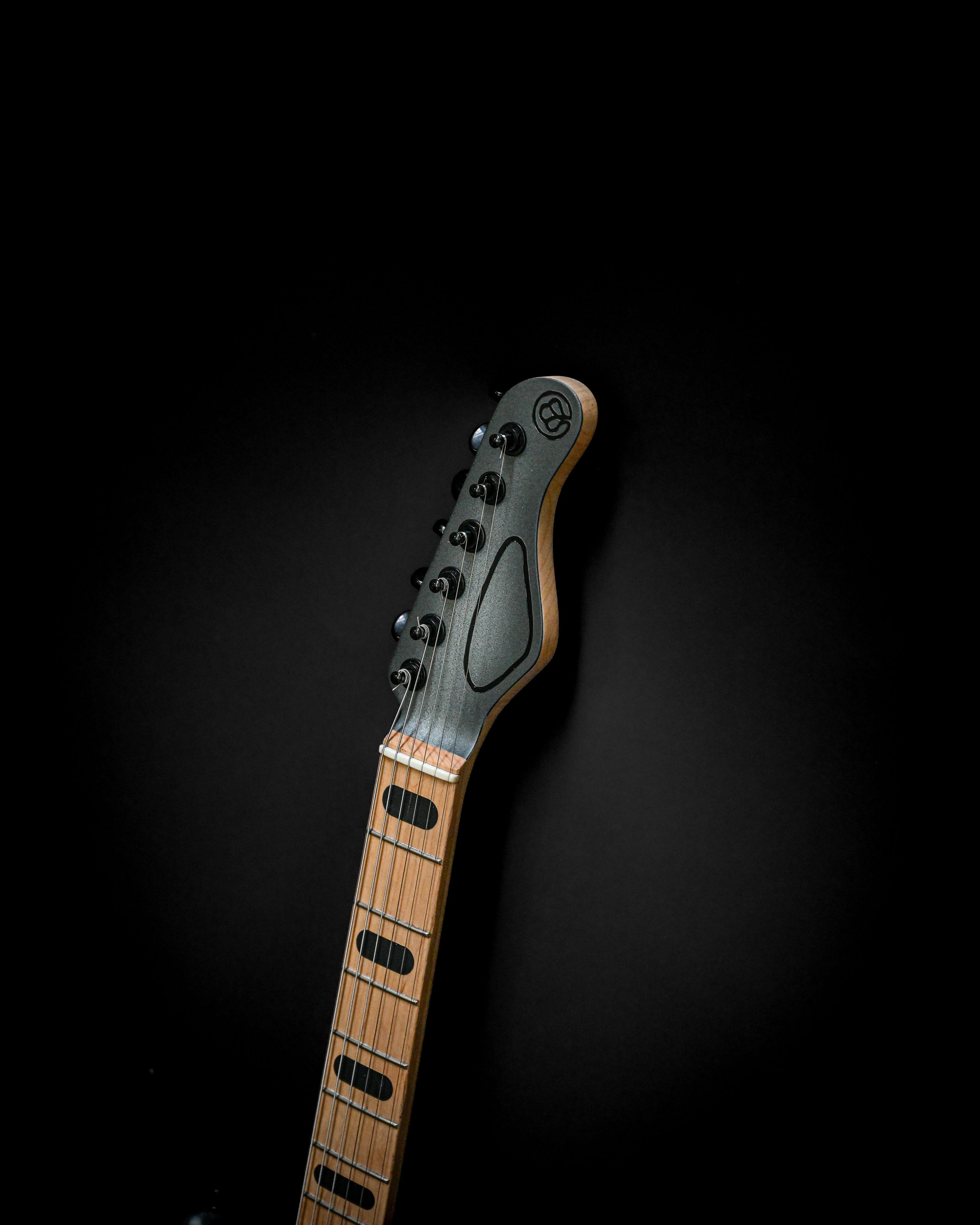 Custom electric guitar in the Sarā 6 - Essential line, highlighting its professional-grade tone and simplicity against a black background.