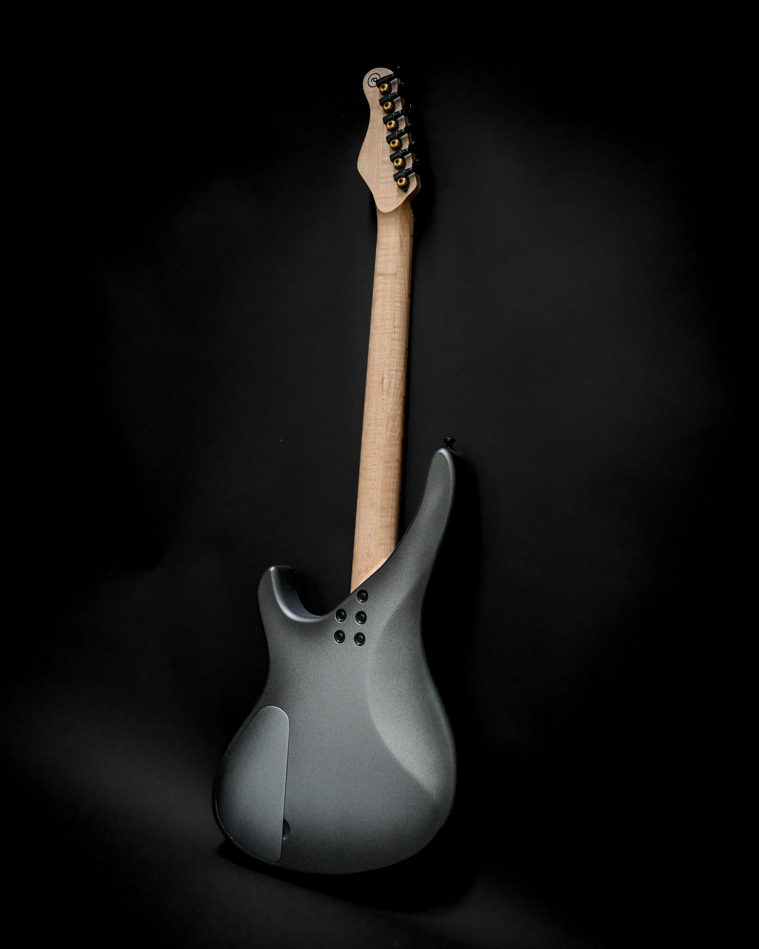 Back view of the Sarā 6 - Essential custom electric guitar, showcasing its sleek design and maple neck on a black background.