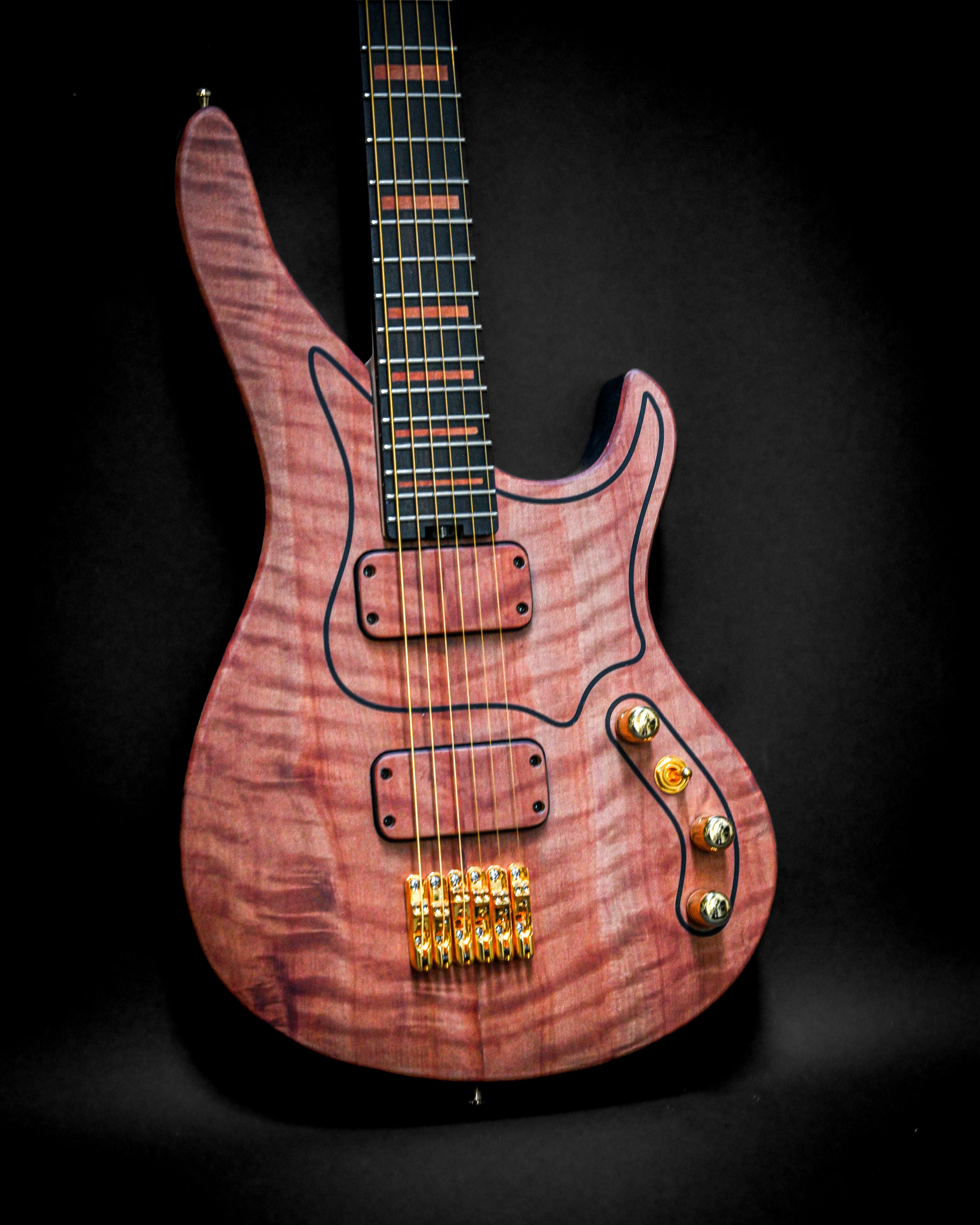 Purple electric guitar with gold hardware and unique wood pattern on a black background.