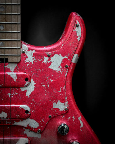 Close-up of Yatē 6 - Essential - Kurenai custom electric guitar body and neck with red finish and weathered details.