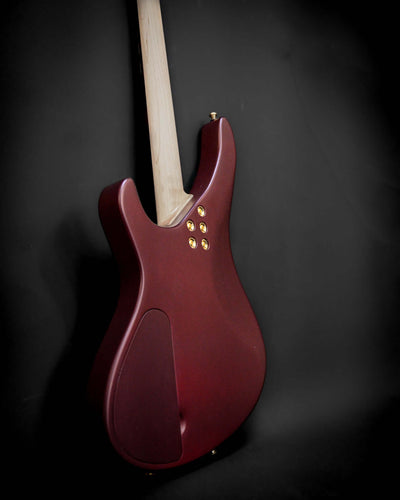 Back view of a Sarā 6 - Essential bass guitar by Belforti, showcasing its sleek design and quality craftsmanship in a dark red finish.
