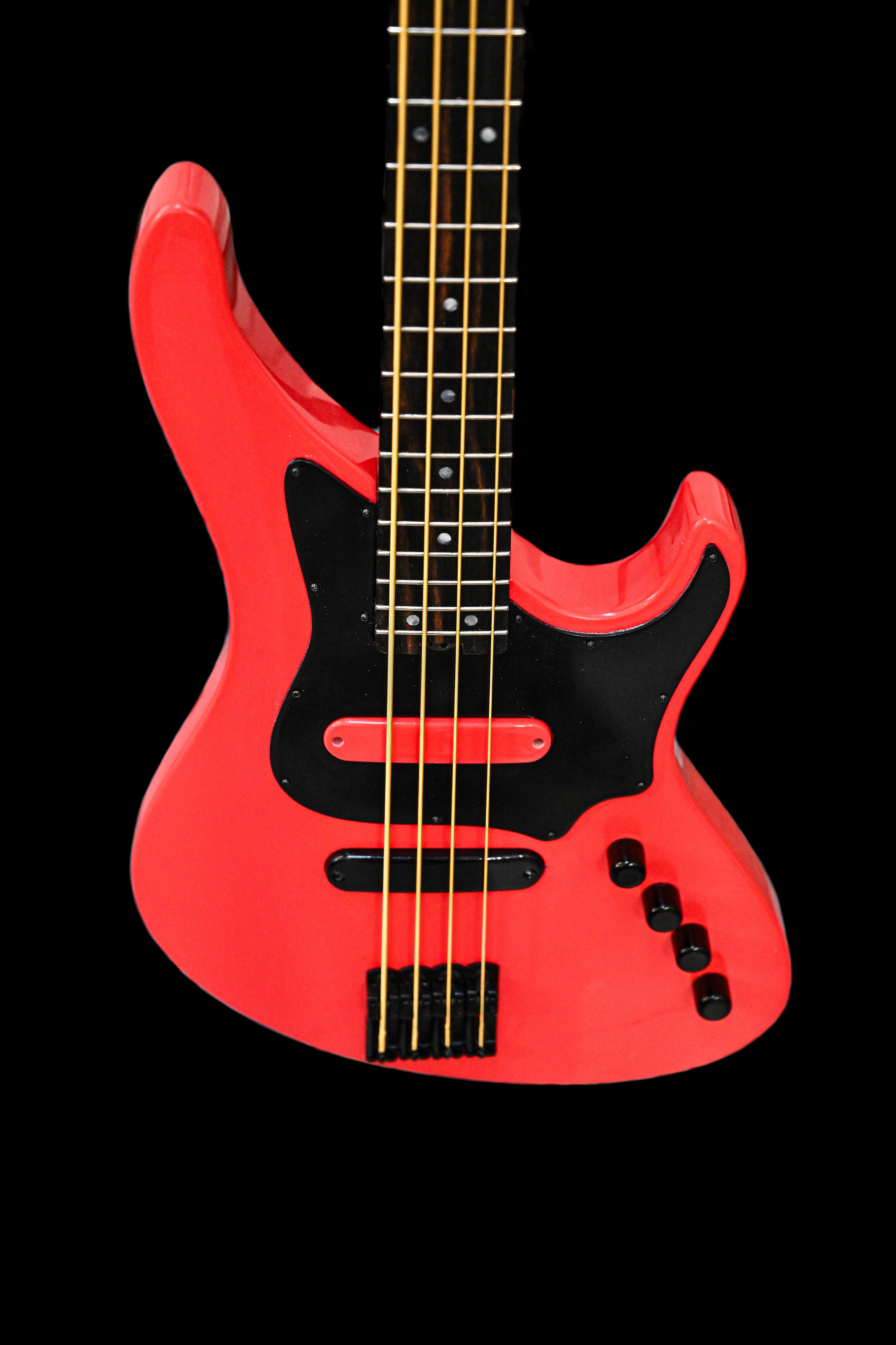 Nahaufnahme des Korpus der E1 Normandy Apple Red Bassgitarre von Belforti Instruments, die das glatte rote Finish und die schwarzen Details hervorhebt.