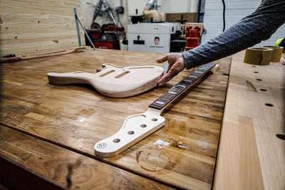 Curso de construcción de guitarras y bajos de 3 semanas en París con Belforti Instruments, donde se muestran el banco de trabajo y los componentes de las guitarras en el taller.