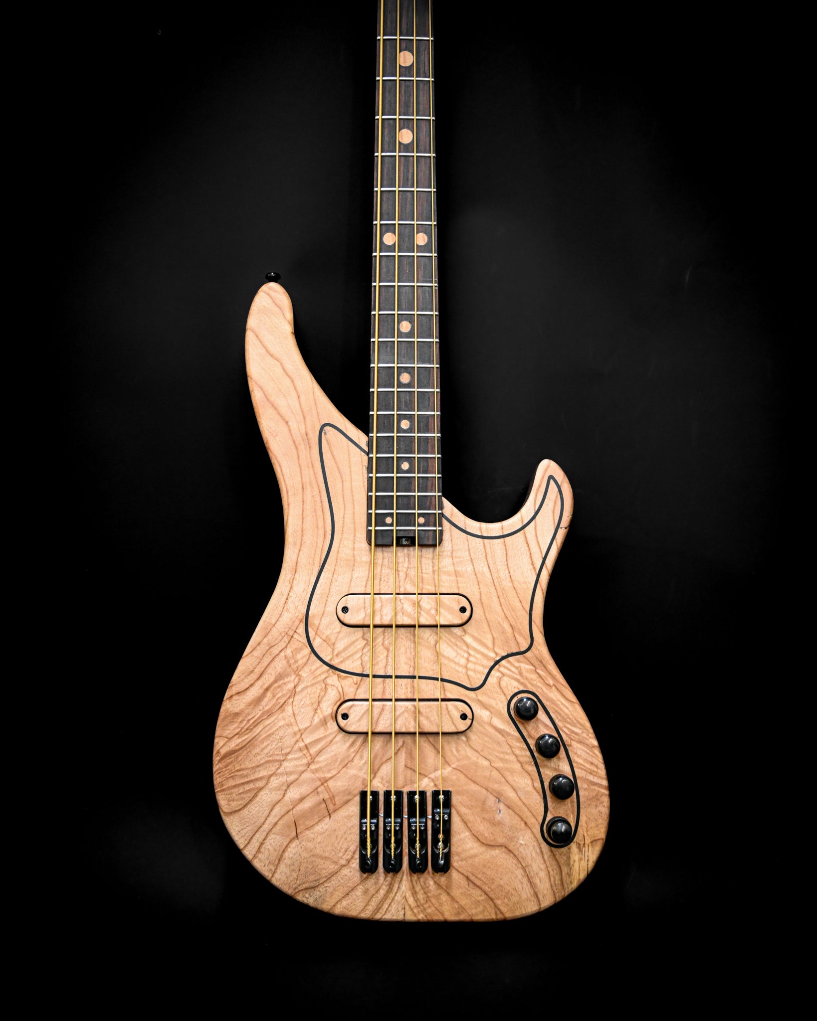 Ángulo lateral del bajo M3 Maple, que revela su contorno distintivo y su artesanía.