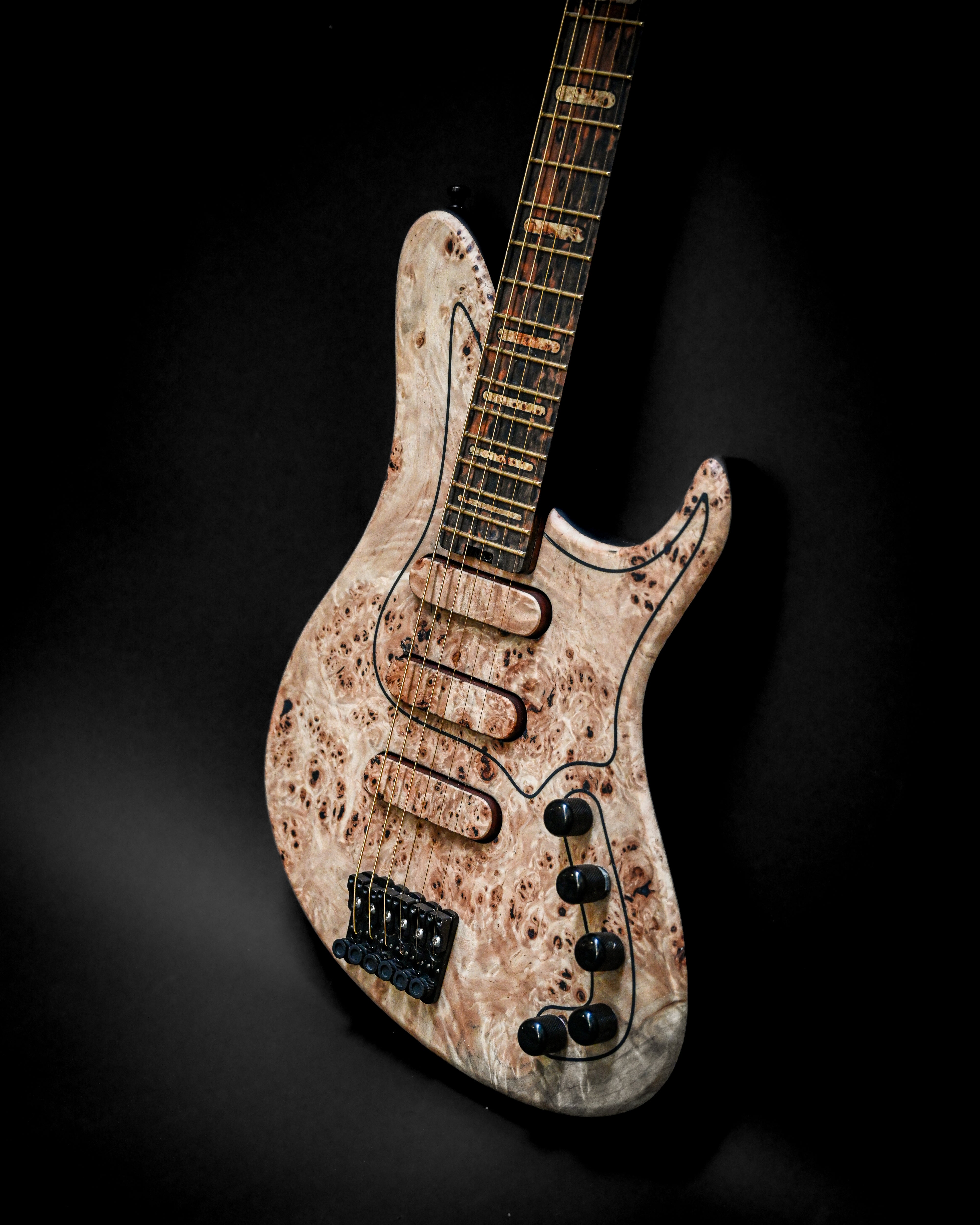 Guitarra eléctrica única con acabado en madera natural sobre fondo negro.