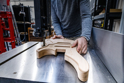 Artisan façonnant le corps d'une guitare dans un atelier pendant le cours de 6 semaines de construction de guitares et de basses personnalisées à Paris.