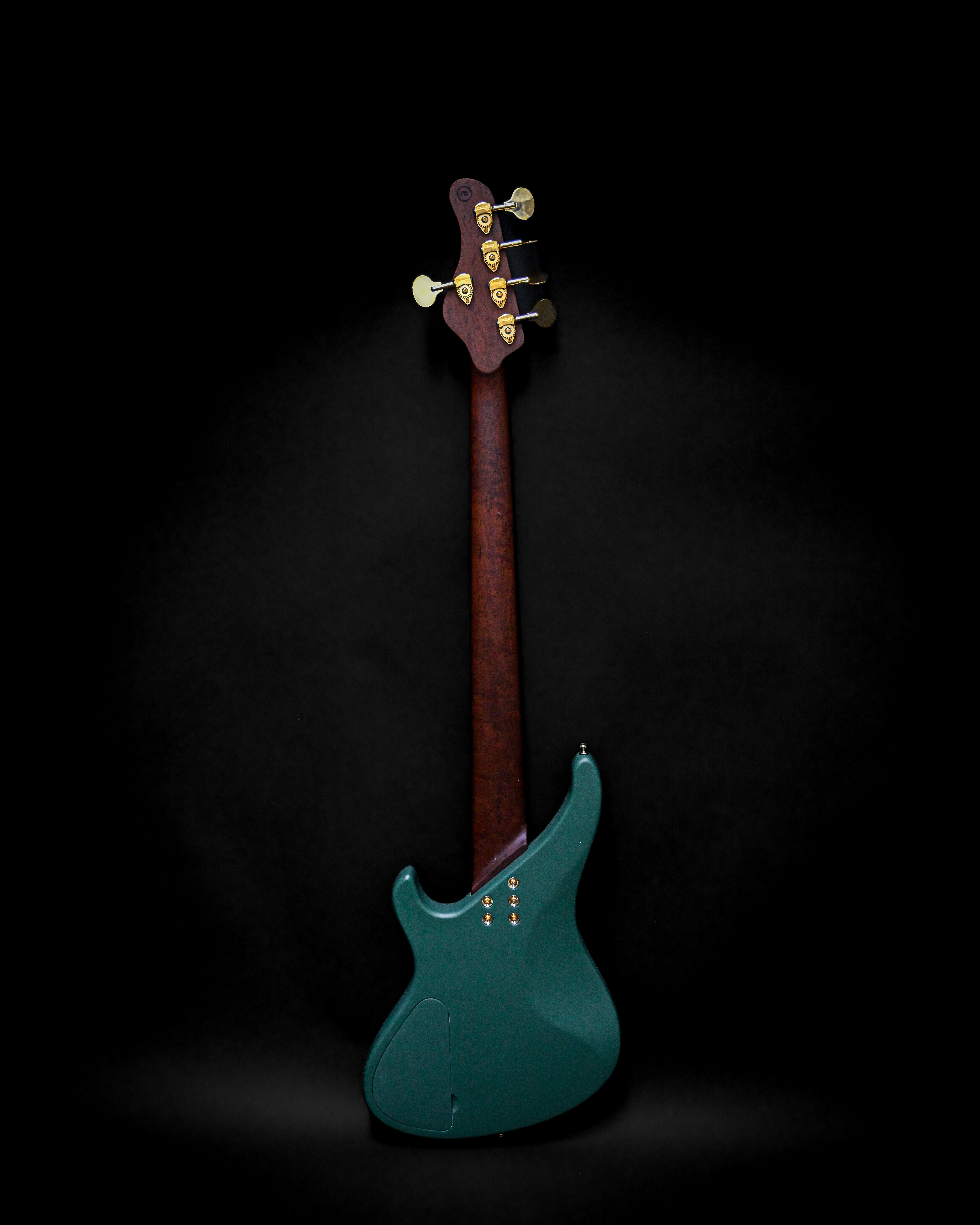 Dos d'une guitare basse électrique avec un corps vert foncé et un manche en bois sur fond noir.