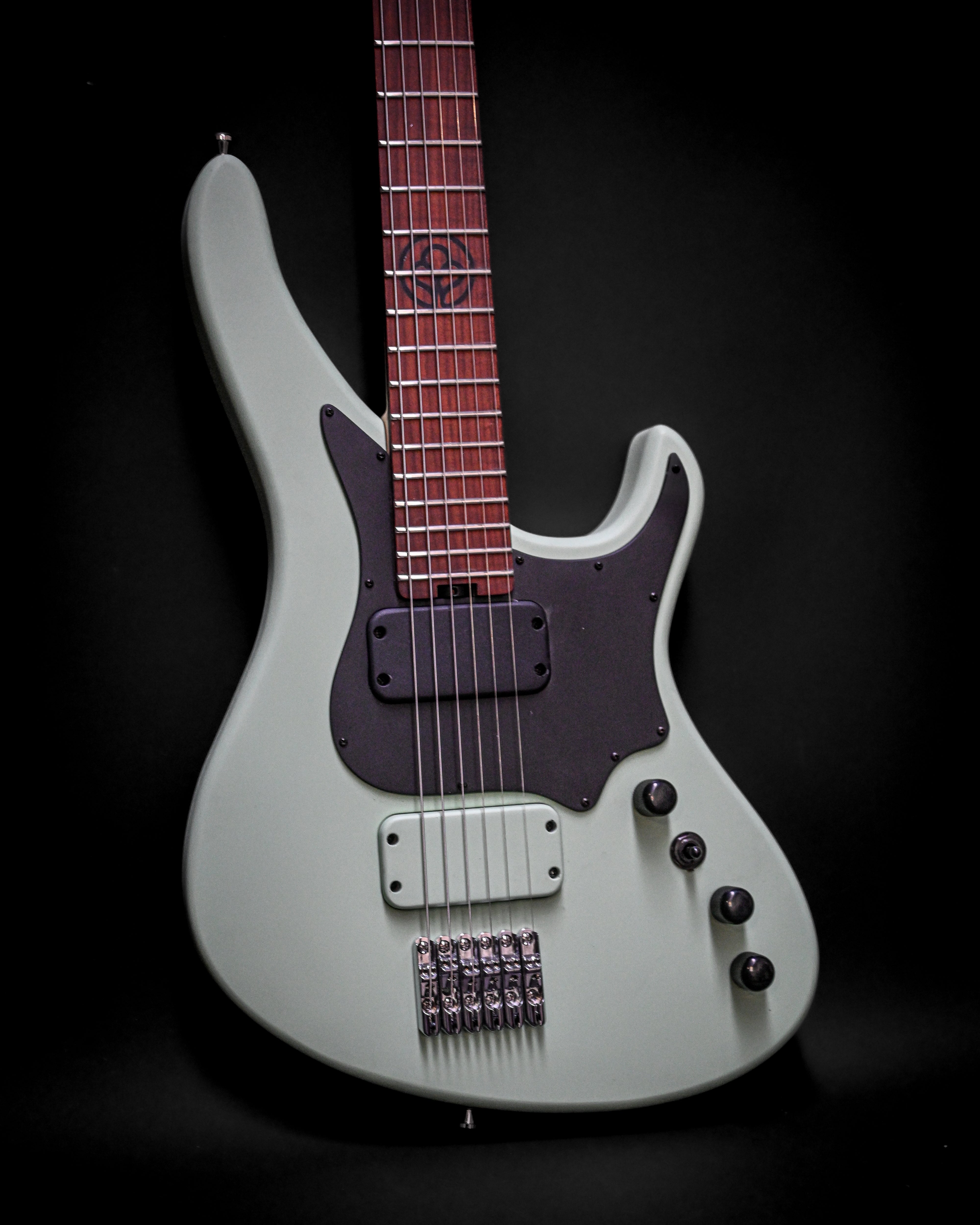 Guitare électrique avec une forme de corps élégante et un pickguard sombre sur fond noir.