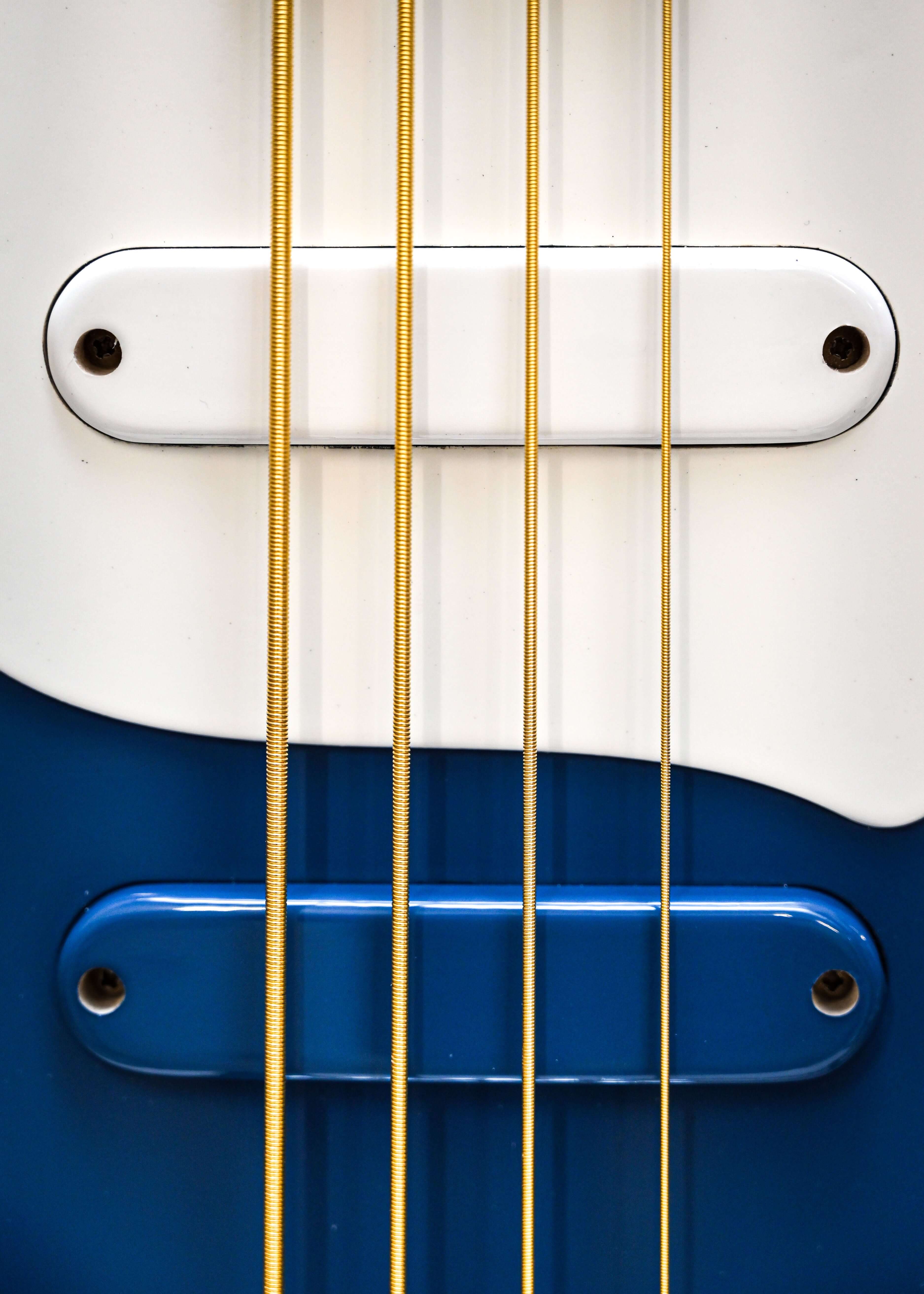 Close-up of guitar strings and pickups on a blue electric guitar, featuring a sleek design. Belforti musical instrument detail.