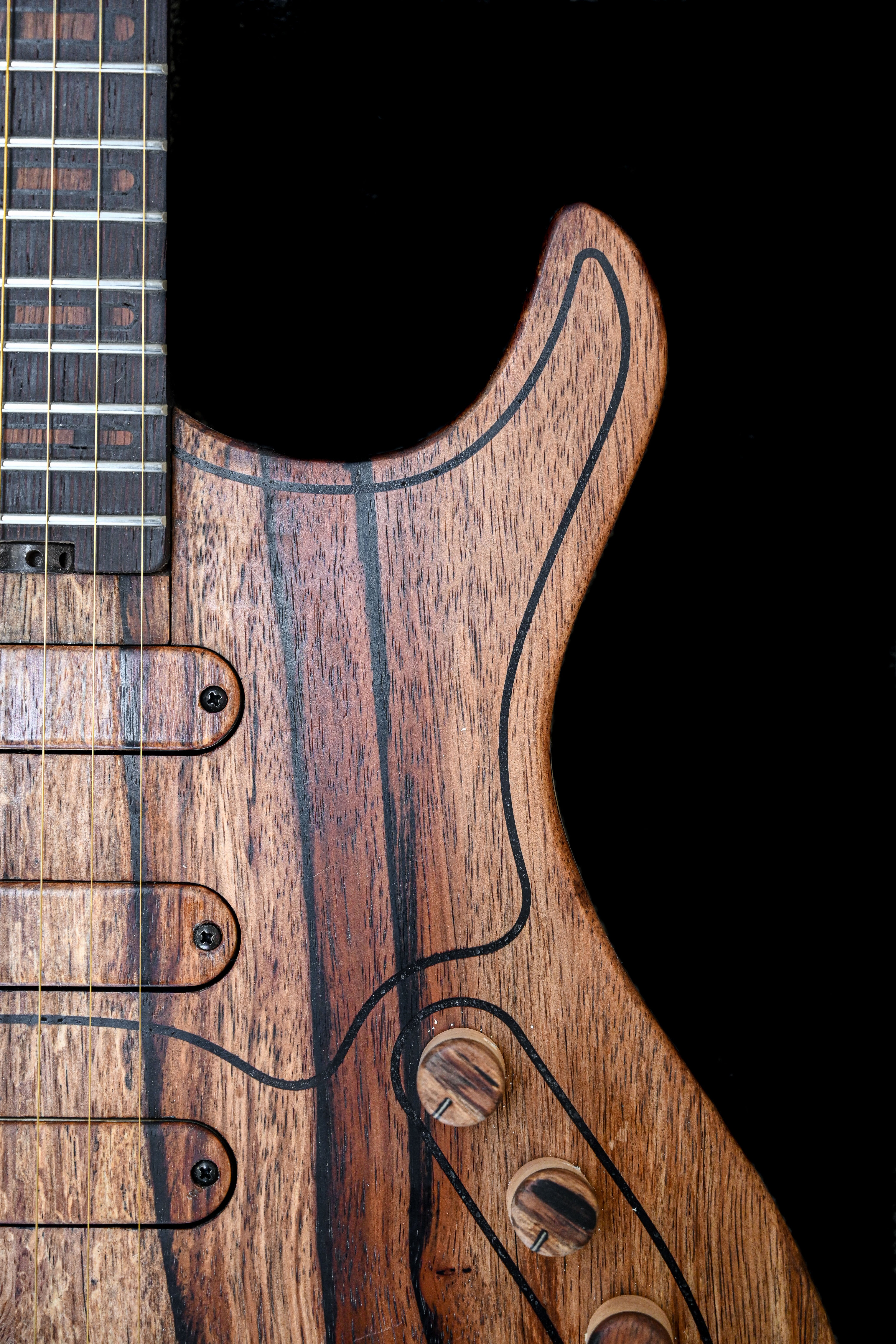 Gros plan sur la guitare de la série M de Belforti Instruments, mettant en évidence les détails du grain du bois et des composants matériels.