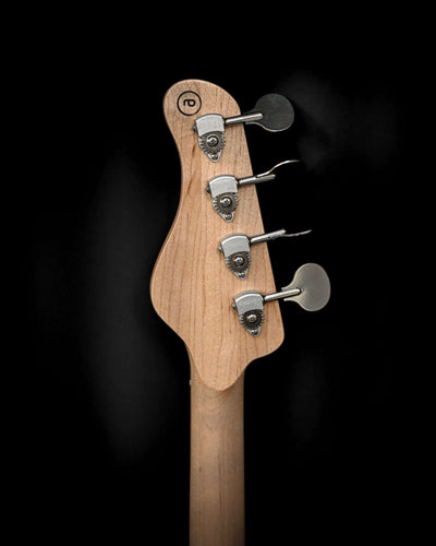 Vēa 4 - Guitare basse Essential de Belforti, mettant en valeur les chevilles d'accordage et la tête de manche sur un fond sombre.