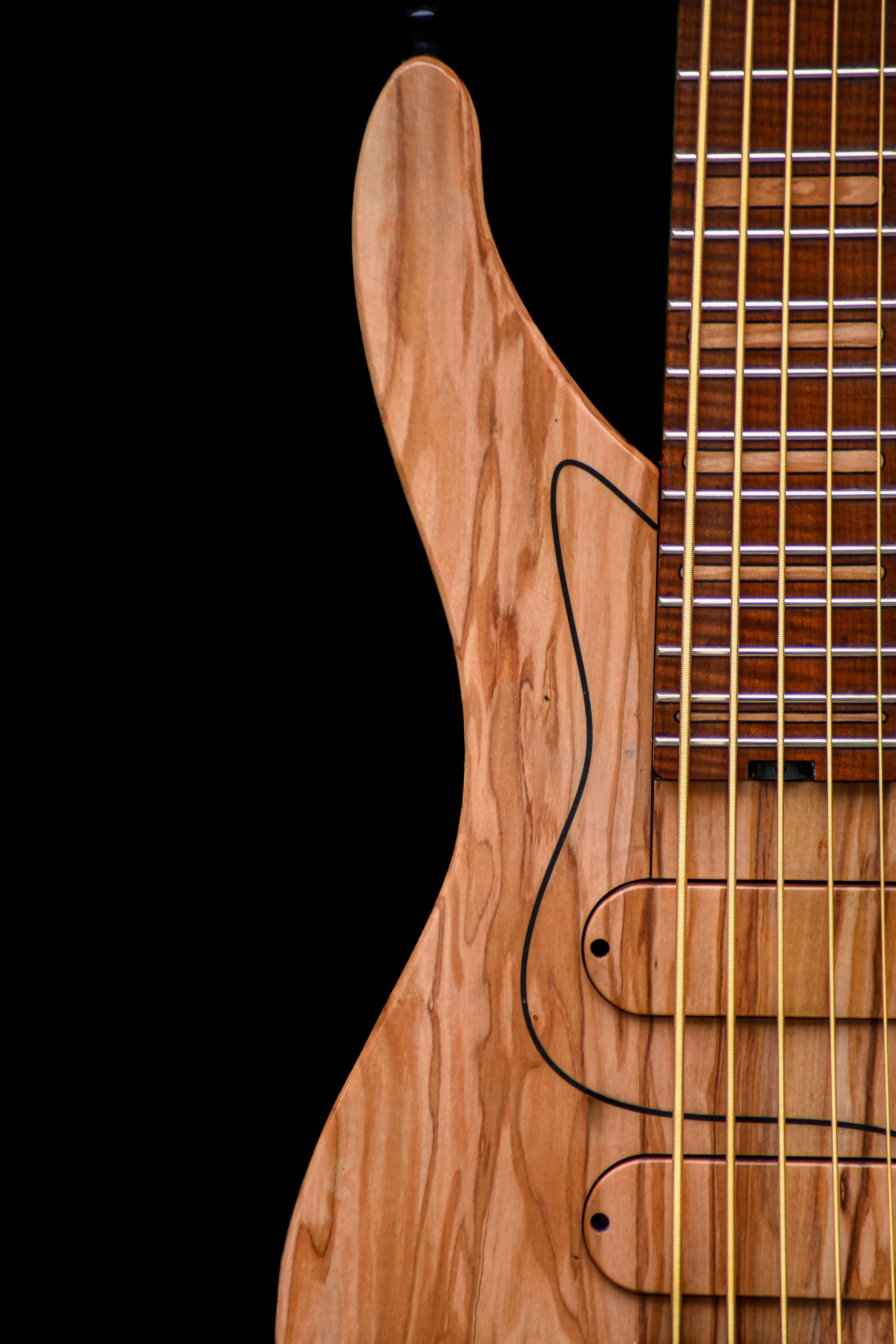 Close-up of the wooden body and strings of a Belforti electric guitar against a black background.