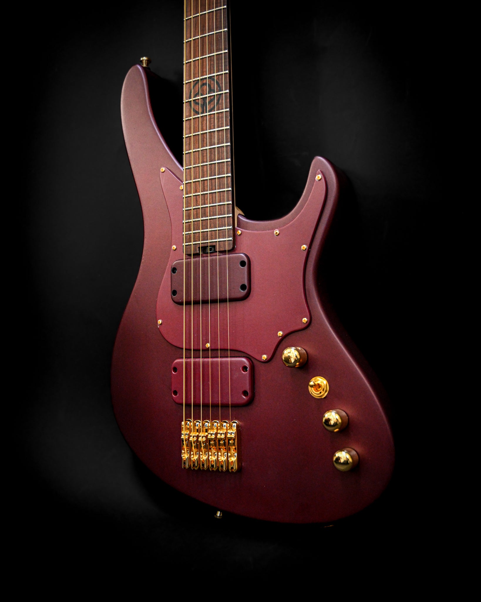 Vista frontal detalhada da guitarra E5 Aventurinrot, destacando os seus captadores e controlos elegantes.