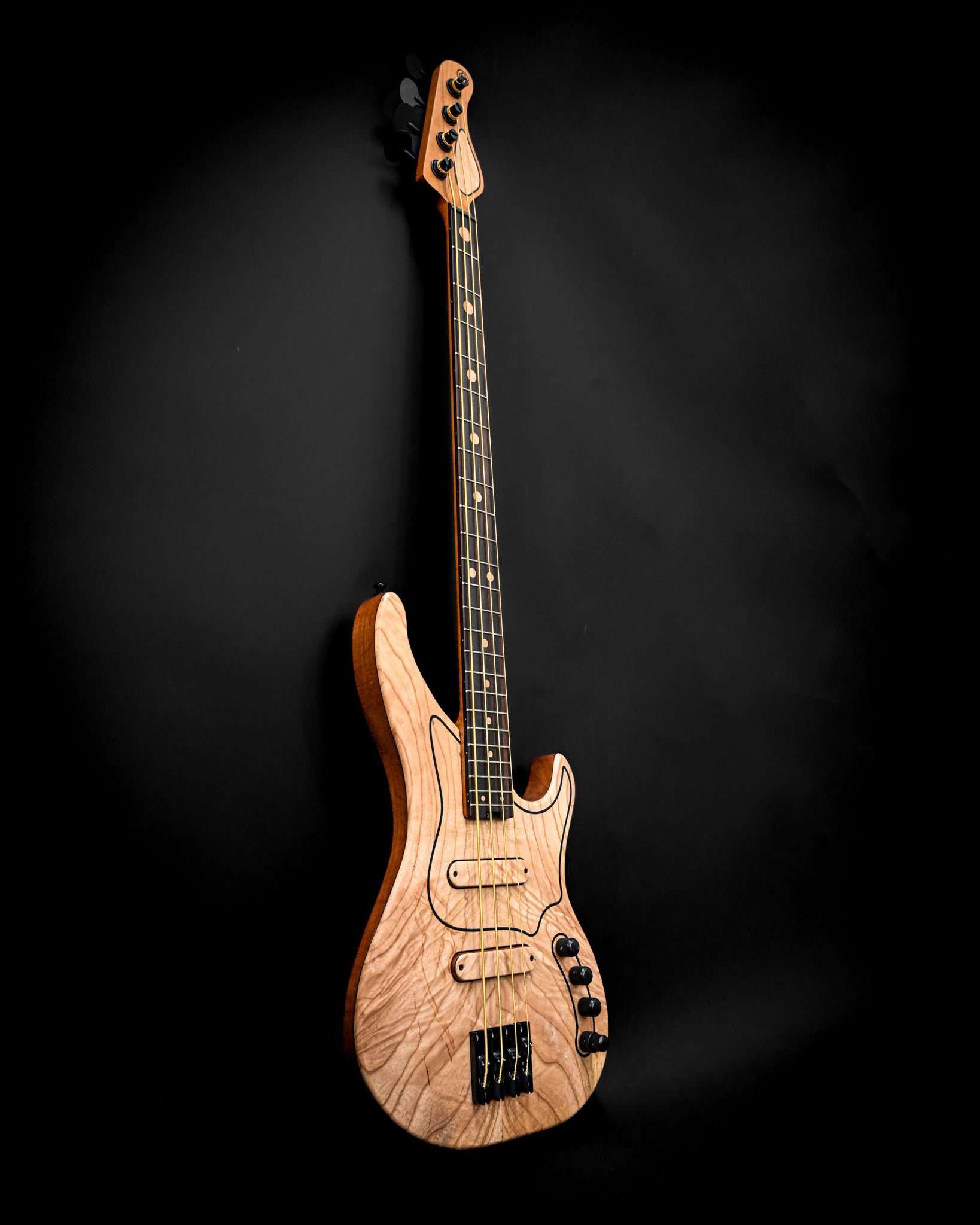 Vista angular da guitarra baixo M3 Maple, capturando a bela textura do maple e os contornos elegantes.