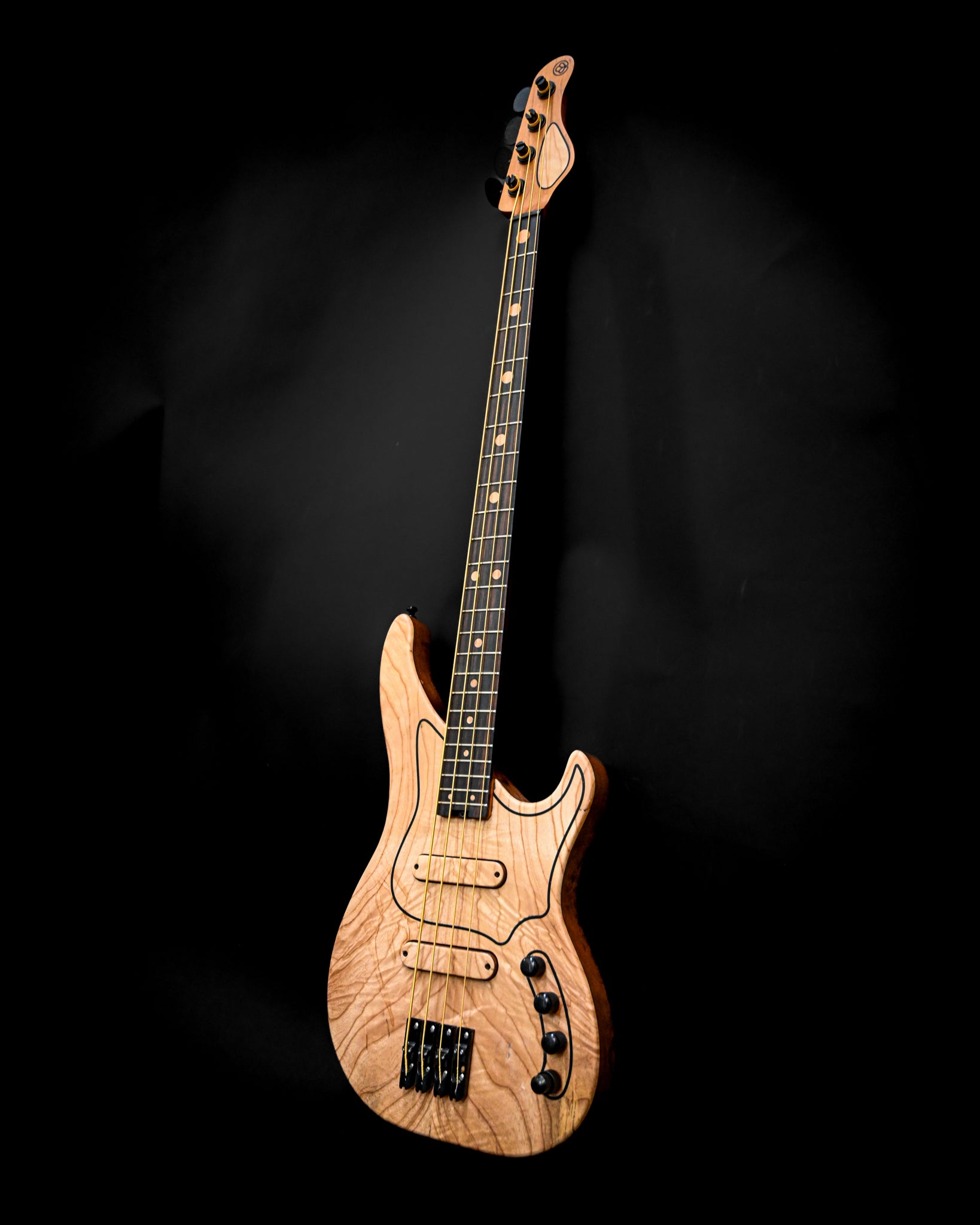 Vista lateral da guitarra baixo M3 Maple, realçando a sua forma única e o acabamento da madeira.