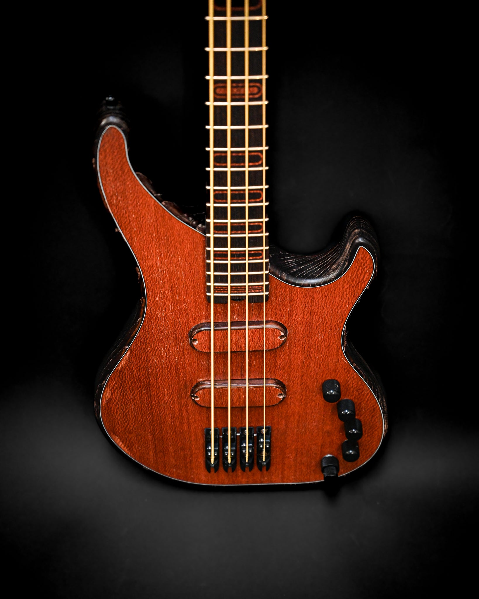 黑色背景下 S3 Lacewood 低音吉他琴弦和拾音器的细节特写。